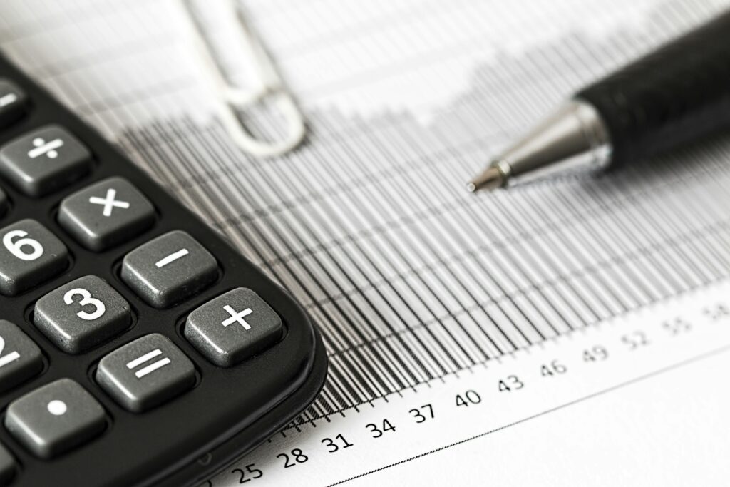 Maximizing Earnings through Smart Purchasing: Passive Income via Credit Card Close-up of a calculator and pen on a bar graph, representing finance and accounting.